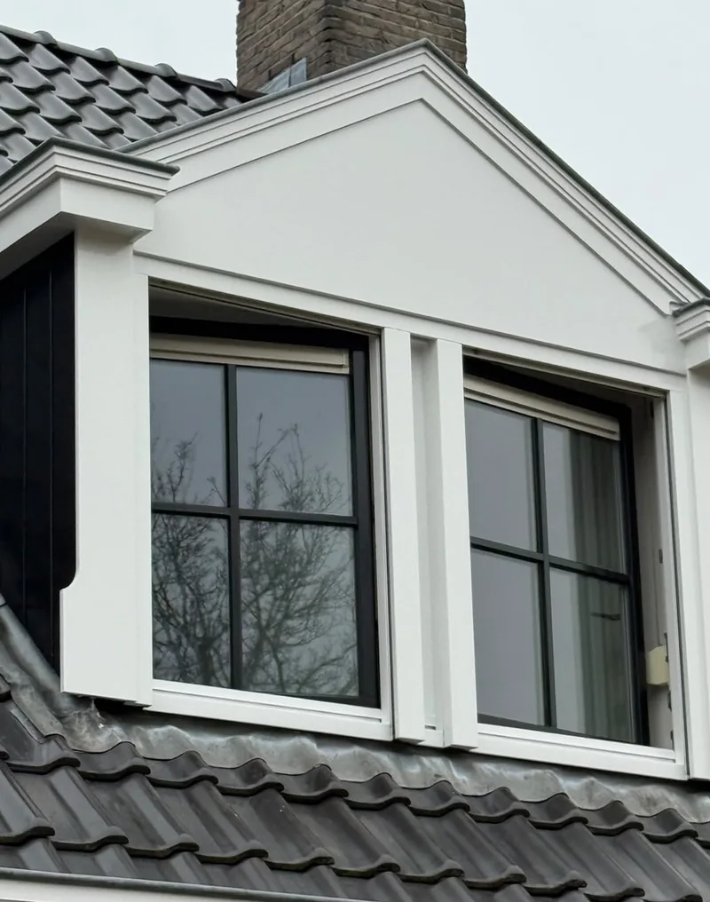 Dakkapel met herstelde en wit afgewerkte kozijnen en lijstwerk